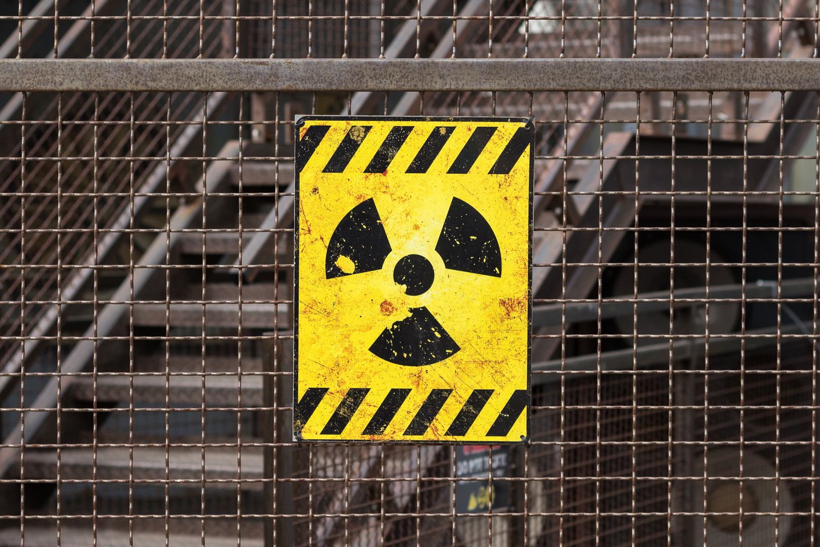 yellow radioactive warning sign on rusty fence 
