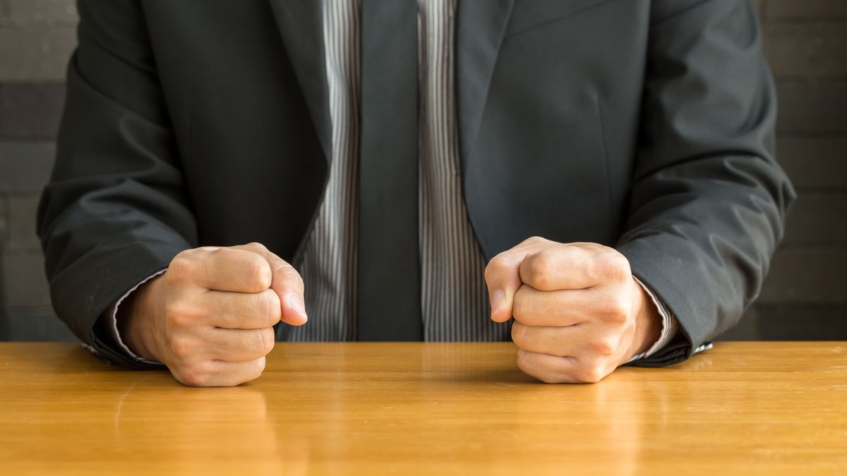 Businessman with clenched fist on the desk at office