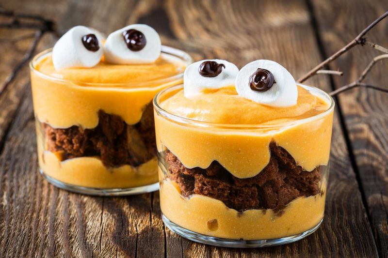 Halloween treats, little monster dessert with chocolate cookies and orange mascarpone cream  topped with big marshmallow eyes 