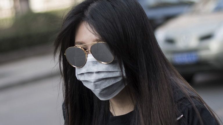 Chinka zakrywająca twarz maską podczas żółtego alarmu dotyczącego zanieczyszczenia powietrza w Pekinie