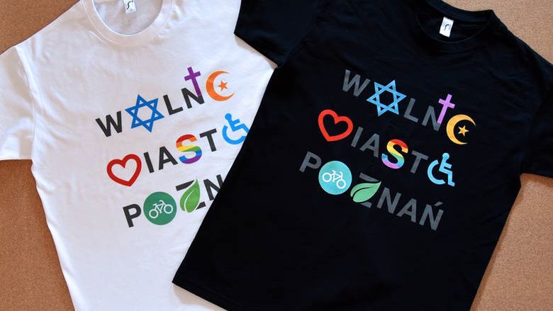 Napis na koszulkach nawiązuje do znaku Coexist, zaprojektowanego przez polskiego grafika Piotra Młodożeńca