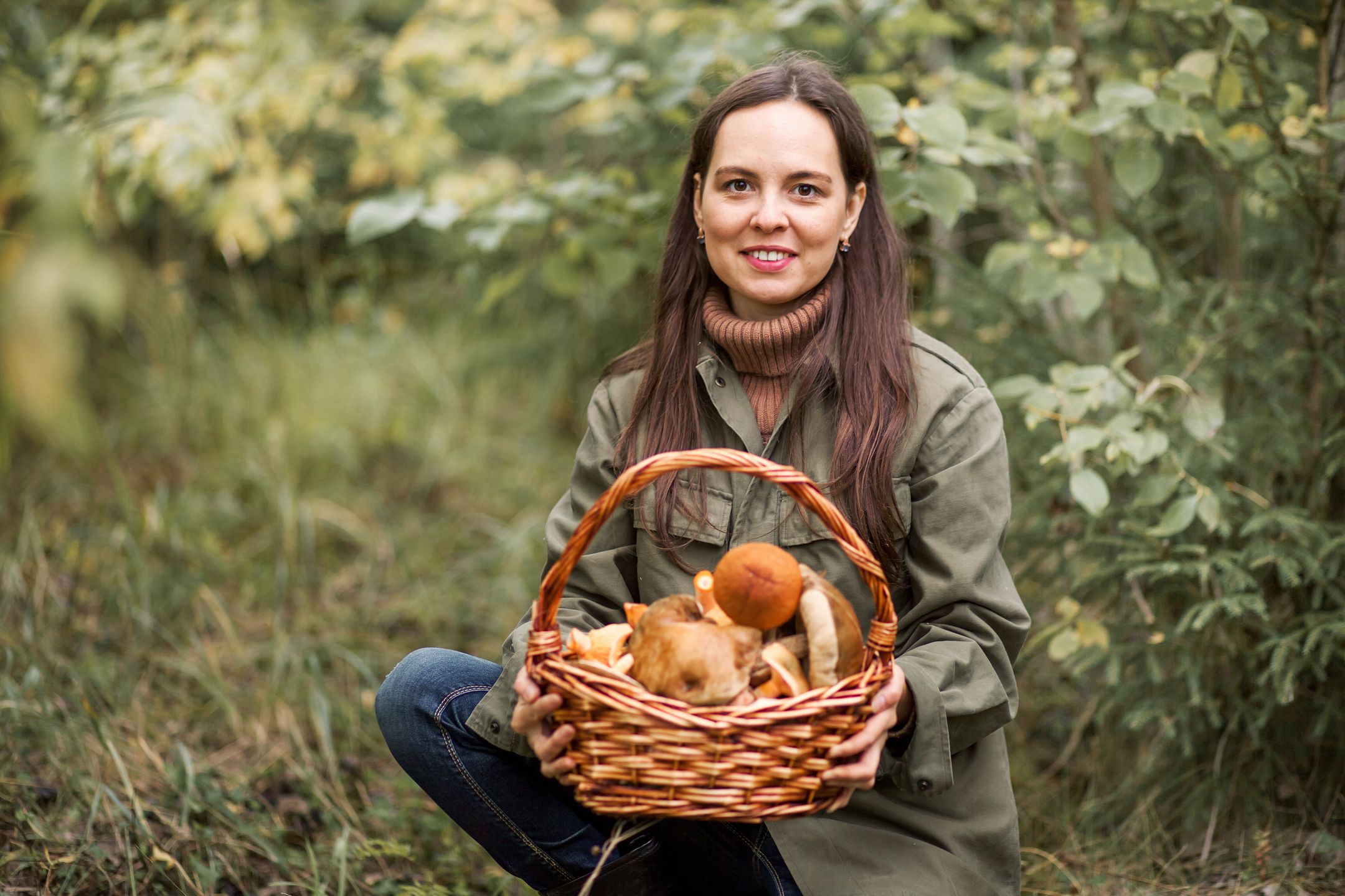 Young woman gathers mushrooms in the forest. 