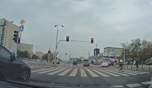 Rowerzysta przejeżdża przez ruchliwe skrzyżowanie na czerwonym świetle