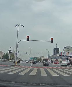 Rowerzysta przejeżdża przez ruchliwe skrzyżowanie na czerwonym świetle